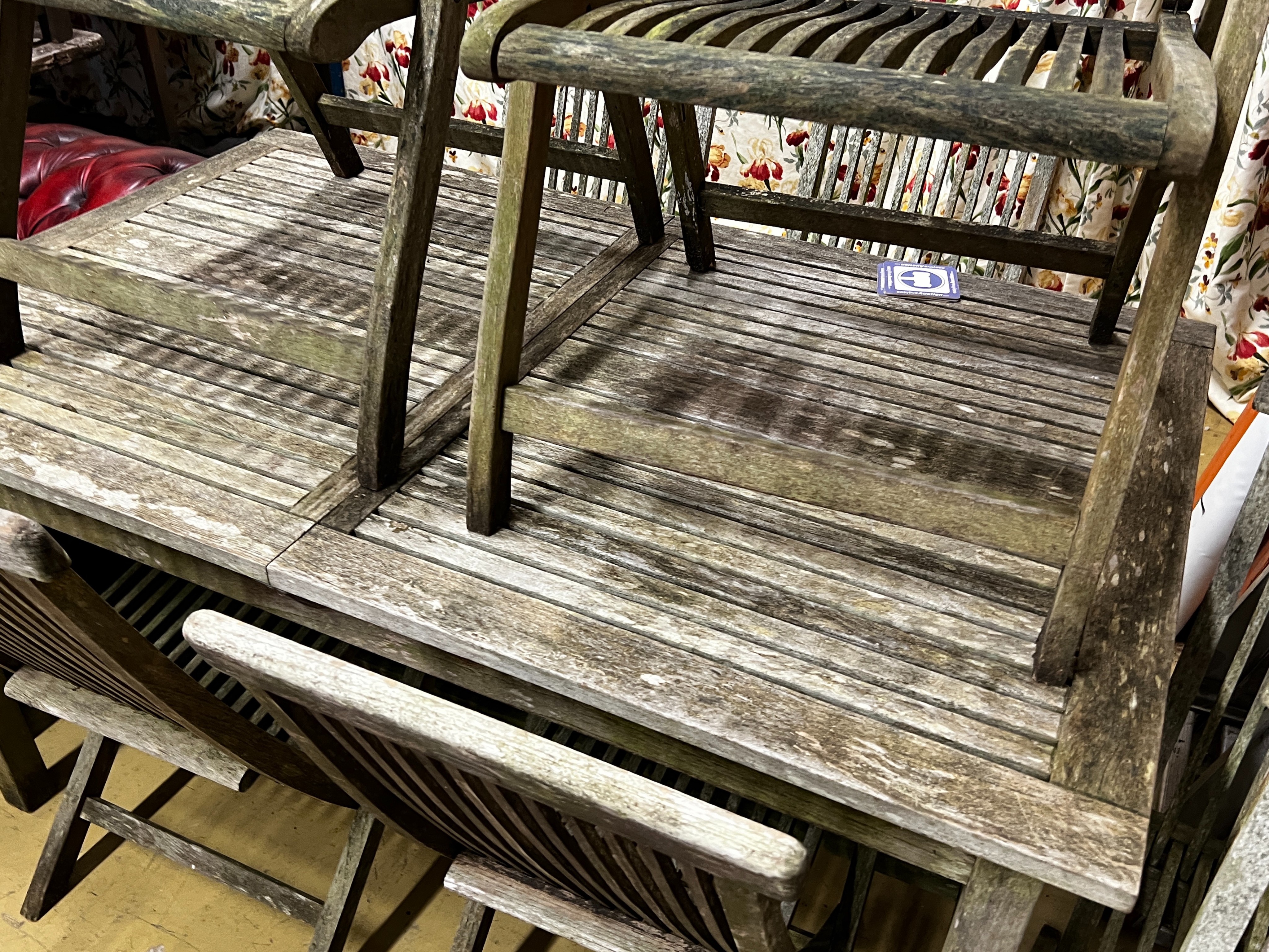 A rectangular weathered teak extending garden table, length 192cm extended, width 89cm, height 76cm together with eight teak folding garden chairs, two with arms